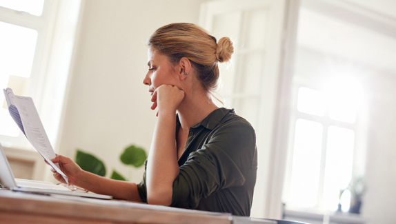woman-looking-at-papers-researching-insurance-coverage-for-catheter-supplies
