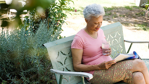 Woman-sitting-reading-drinking-water-managing-neurogenic-bladder