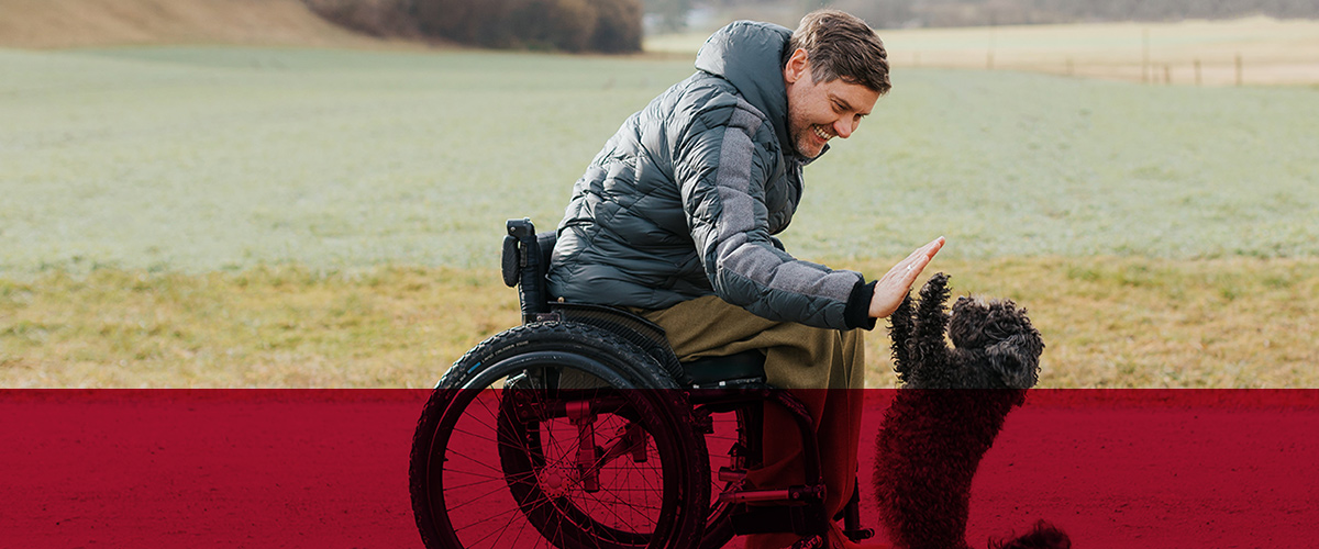 man-in-wheelchair-high-fiving-toy-poodle-world-continence-week