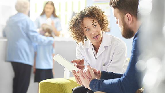 clinician-meeting-with-patient-sharing-Hollister-ostomy-educational-booklet-575x325