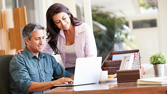 Latinex-couple-using-laptop-on-desk-at-home-ostomy-spanish-resources_575x325