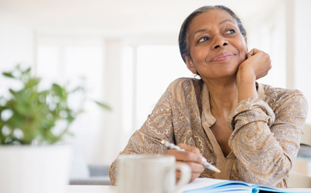 woman-writing-at-desk-why-keep-peristomal-skin-healthy-450x280